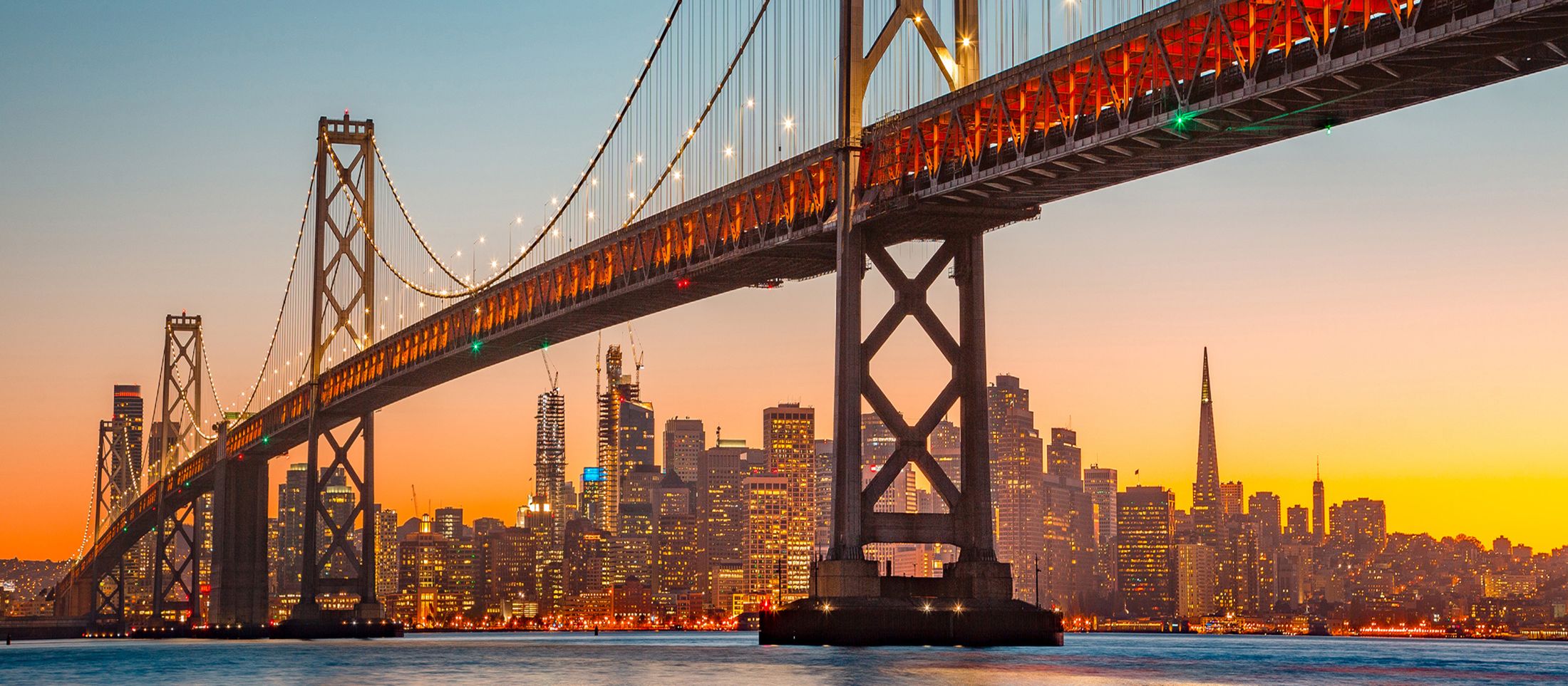 Bay Bridge with San Francisco skyline at sunset.