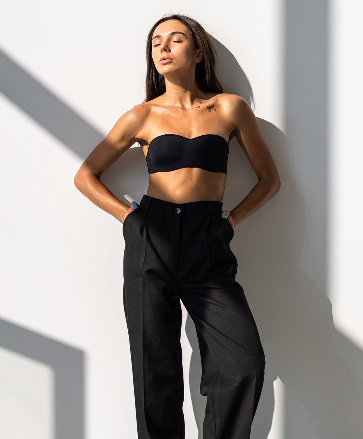 Fashion model in black outfit against a wall.