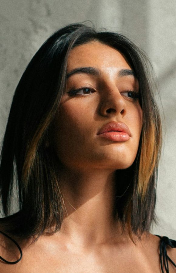 Young woman with straight hair, looking thoughtfully upwards.