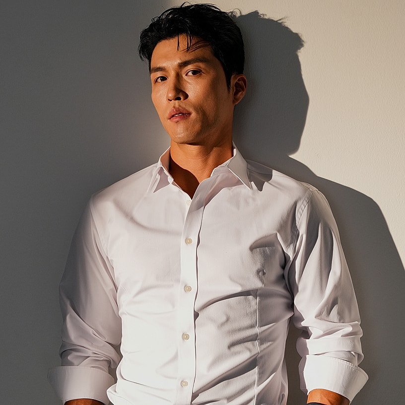 Man in white shirt against a wall.