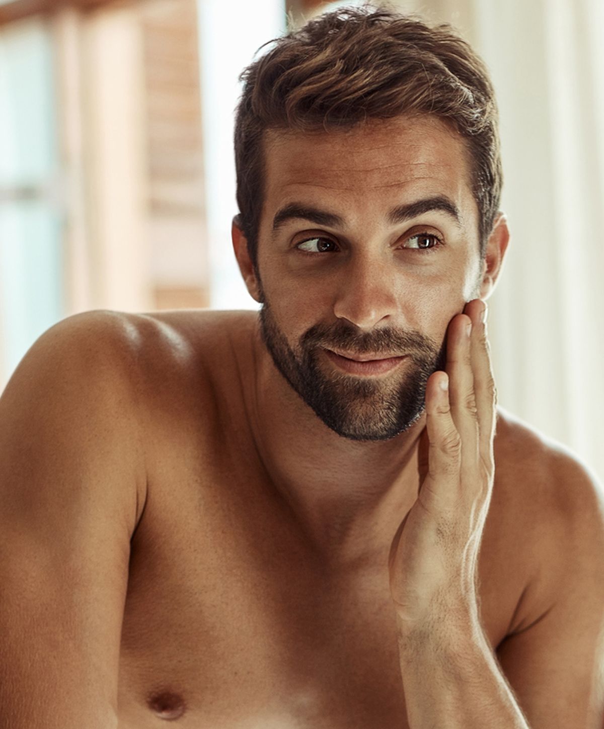 Man touching his face, appearing thoughtful and relaxed.