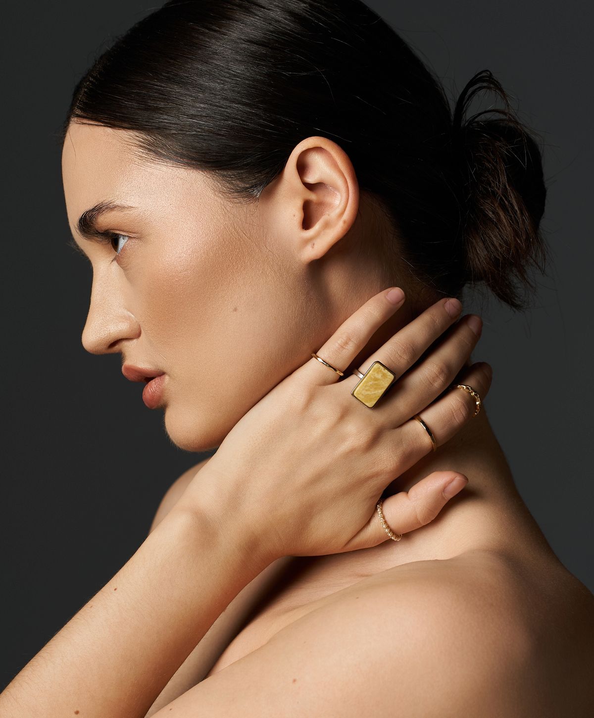 Model showcasing elegant jewelry against dark background.