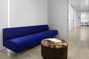 Modern waiting area with blue couch and ottoman.