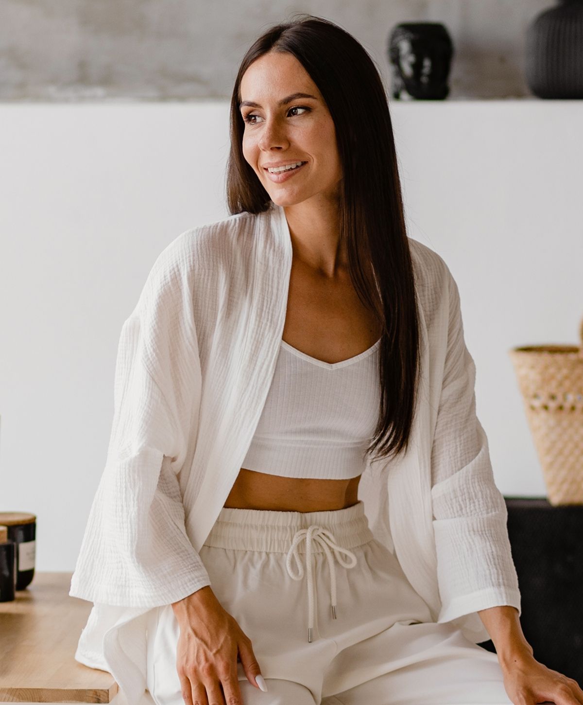 Woman in casual white outfit, smiling.