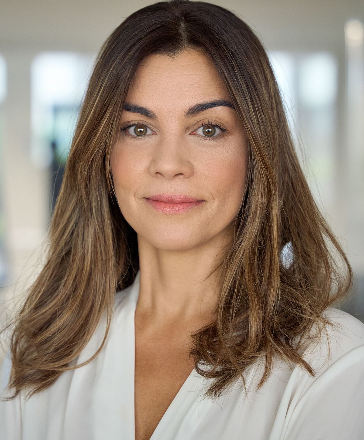 Woman with long hair and neutral expression.