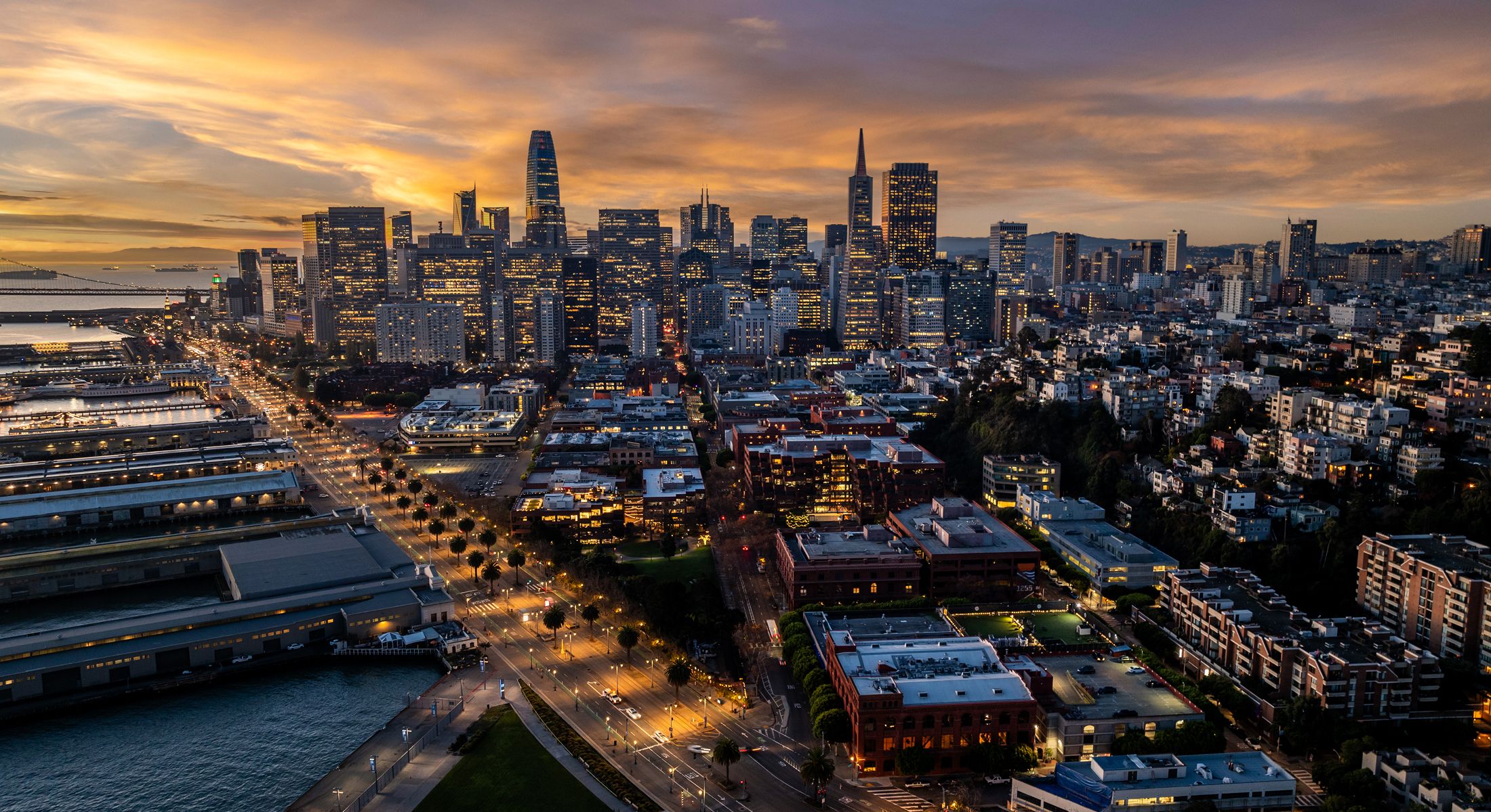 San Francisco skyline at sunset with illuminated buildings.