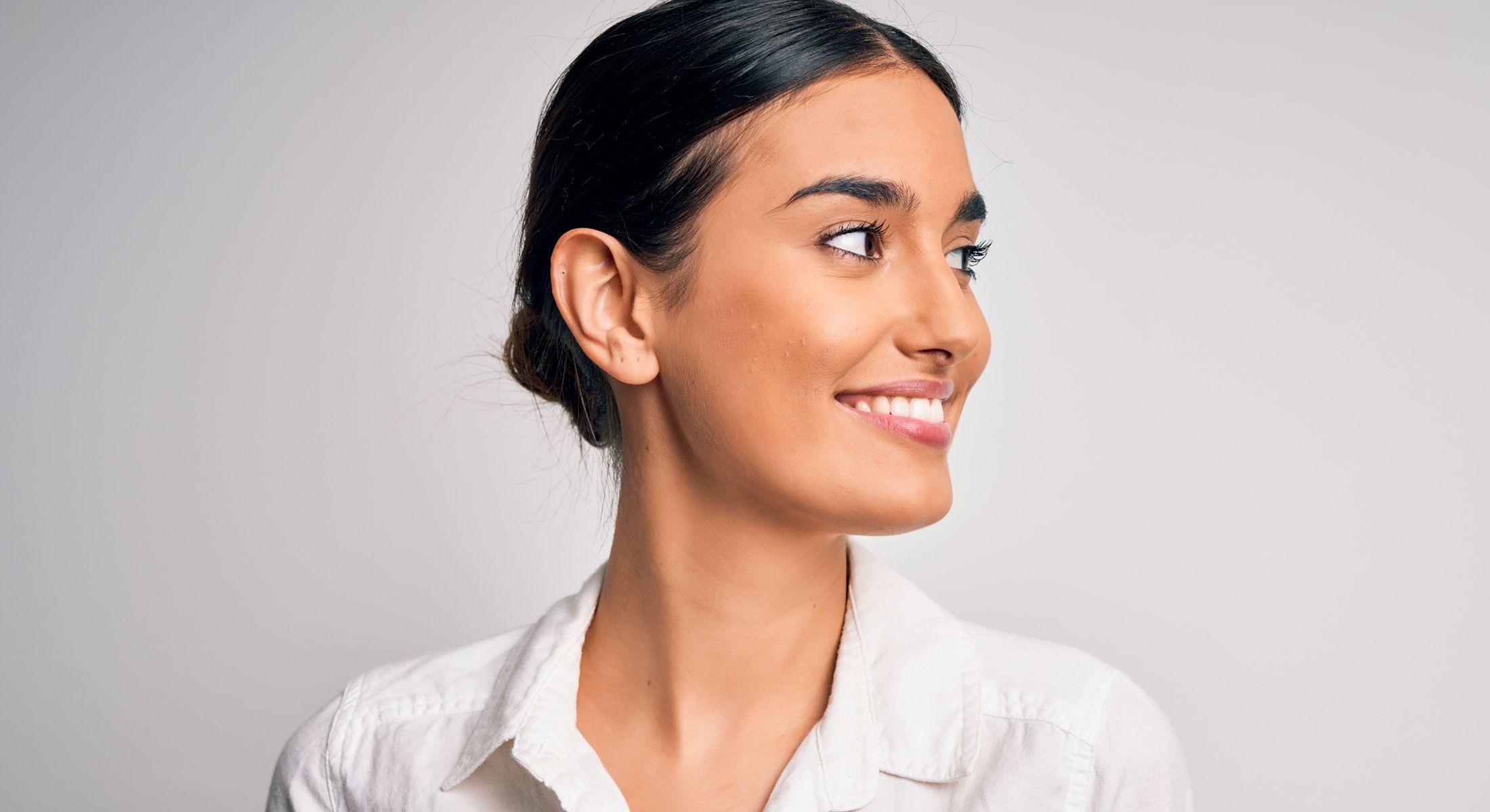 Smiling woman in white shirt against plain background.