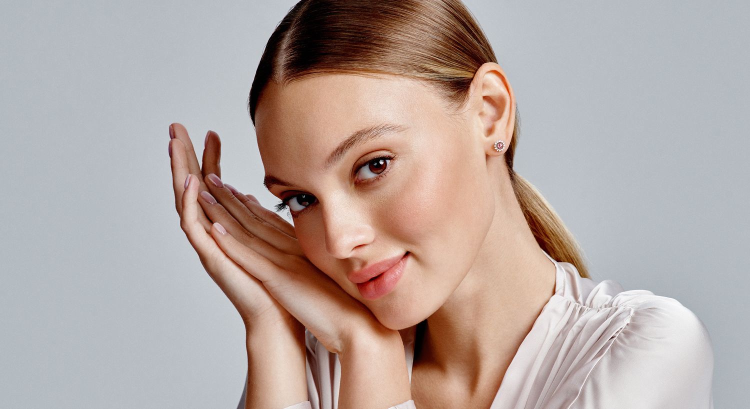 Blonde woman with rings and a thoughtful expression.