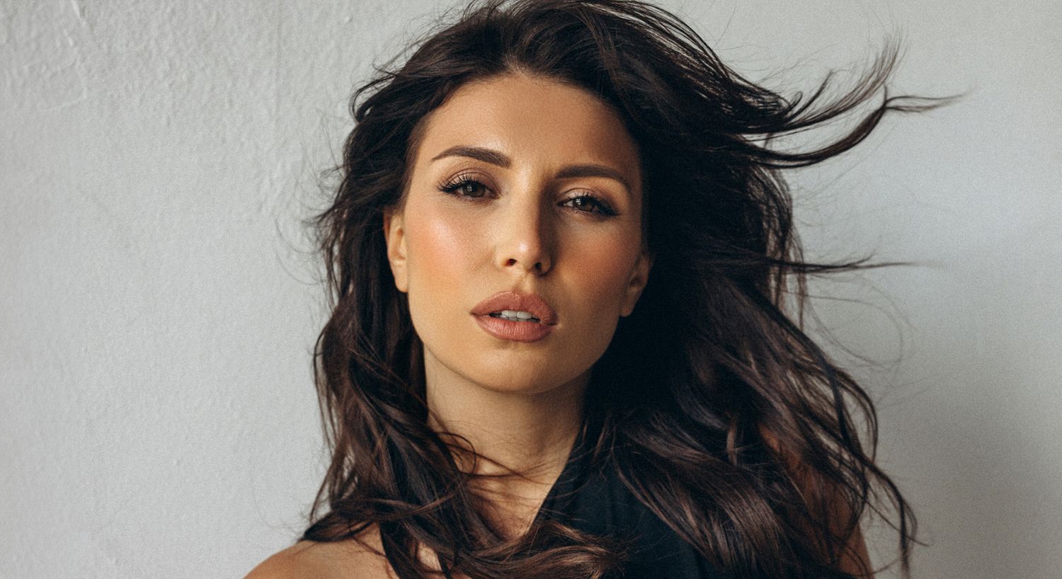Woman with flowing hair against a neutral background.