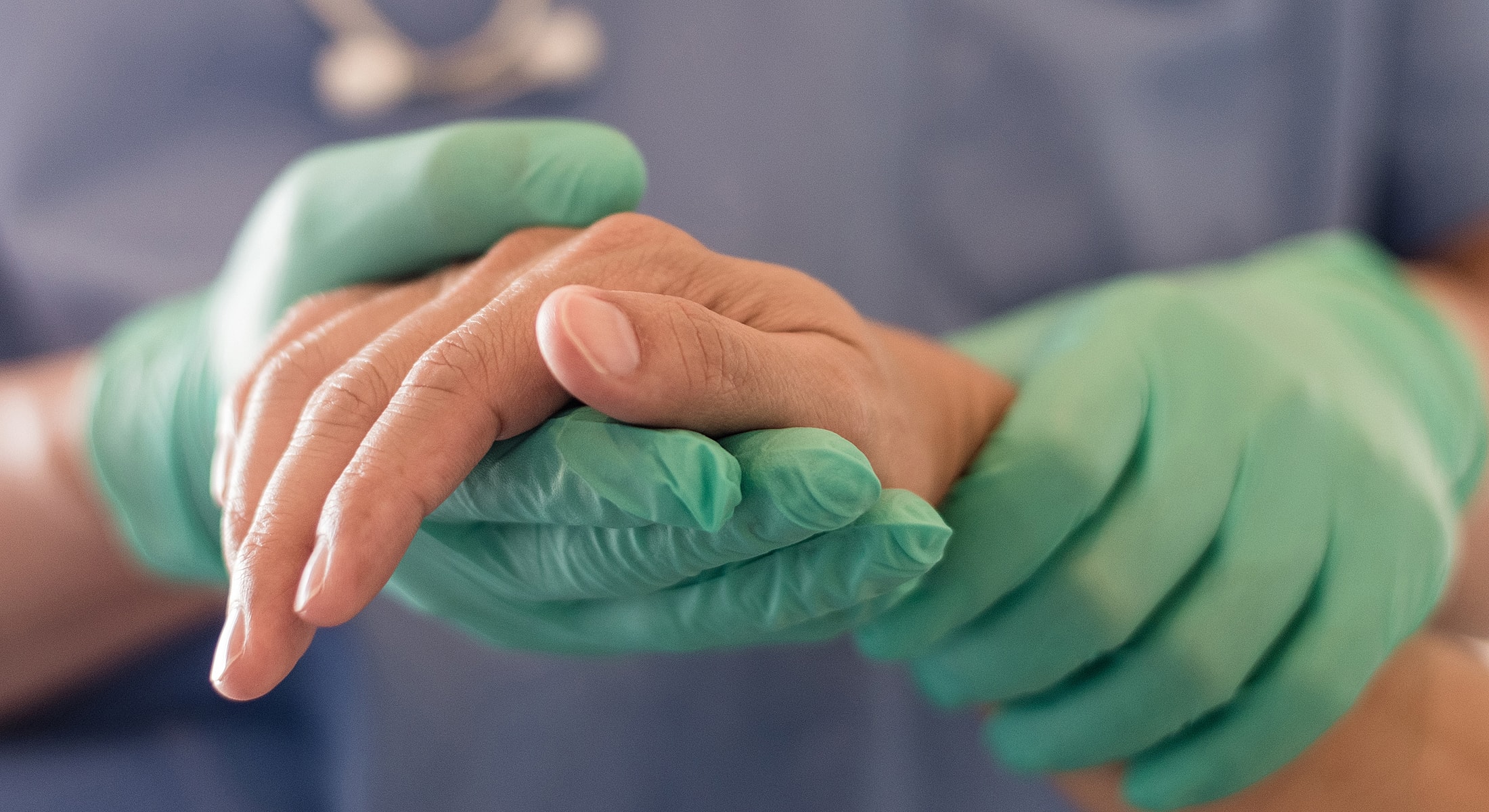 Healthcare professional gently holding patient's hand.